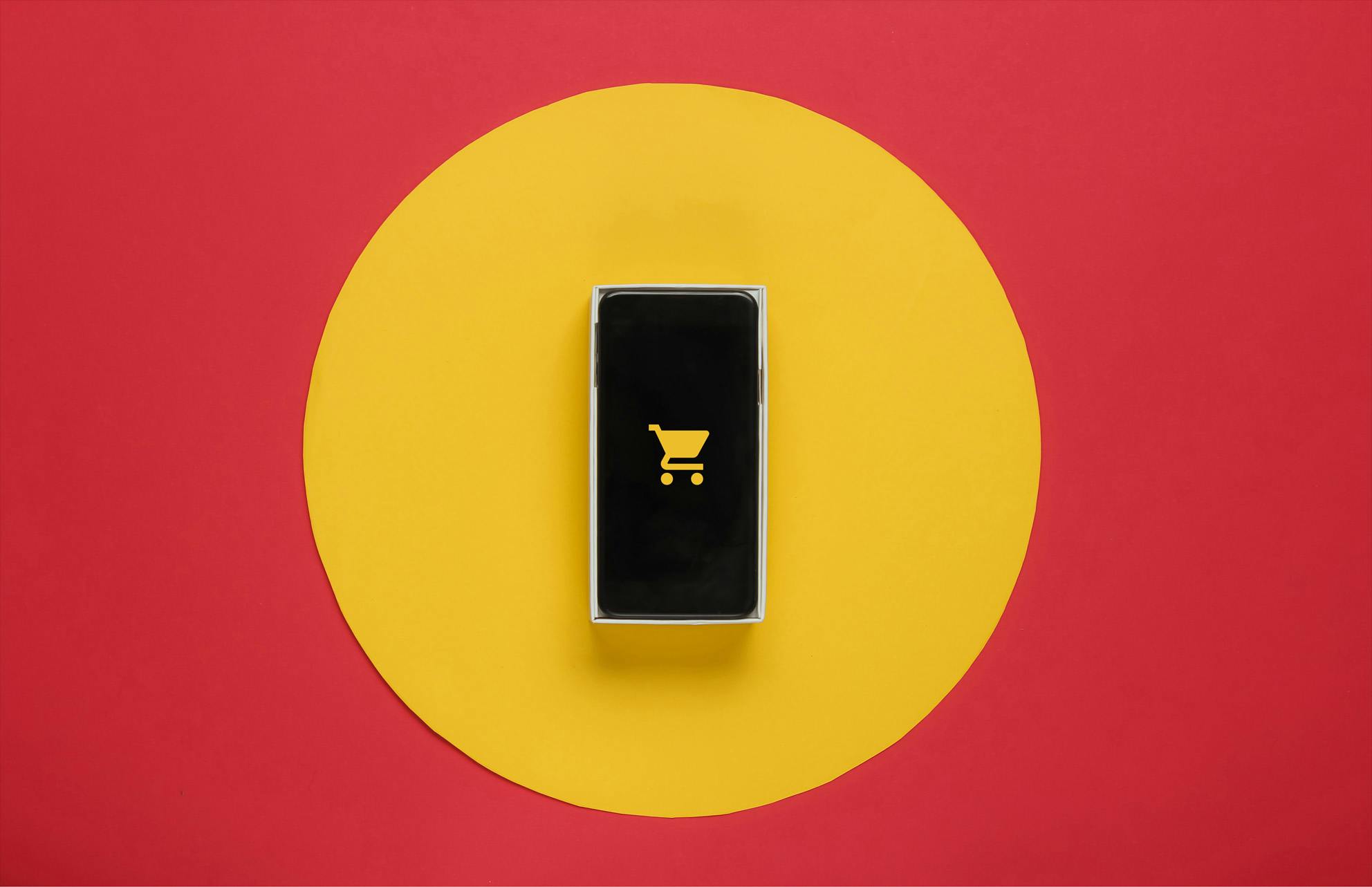 mobile phone with shopping cart icon on yellow circle on red background