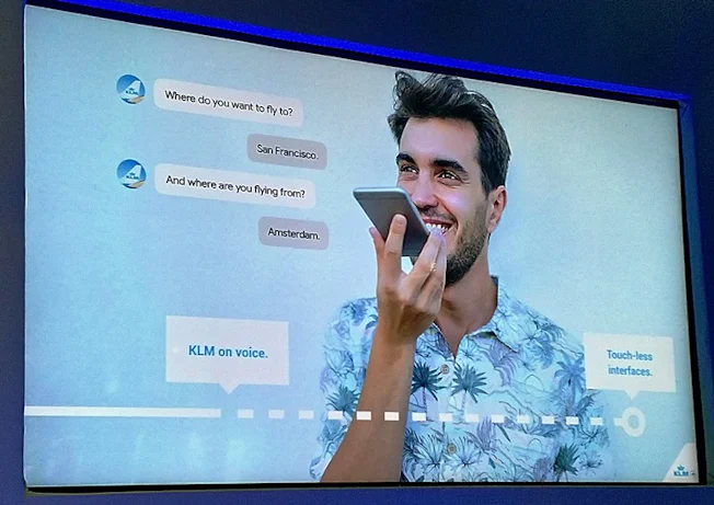 Presentation slide of a man using his mobile to converse with a KLM bot using voice.