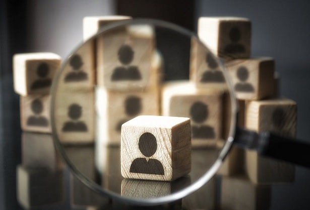 Stock image of wooden blocks depicting customers, with one magnified by a magnifying glass