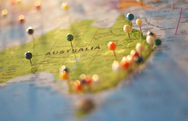 A map of Australia with round-headed colourful pins stuck into it.