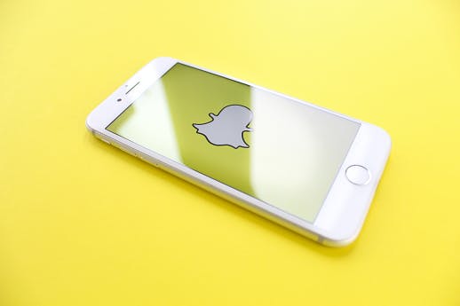 Smartphone displaying Snapchat logo against a yellow background