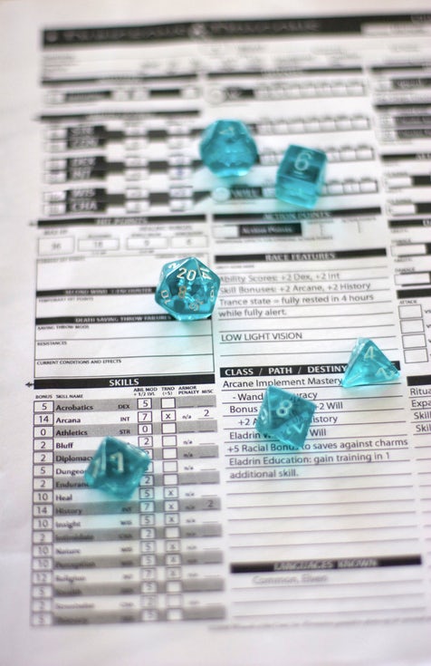 A Dungeons and Dragons character sheet with six translucent turquoise dice on top