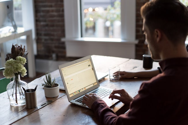 man at table with laptop and plant