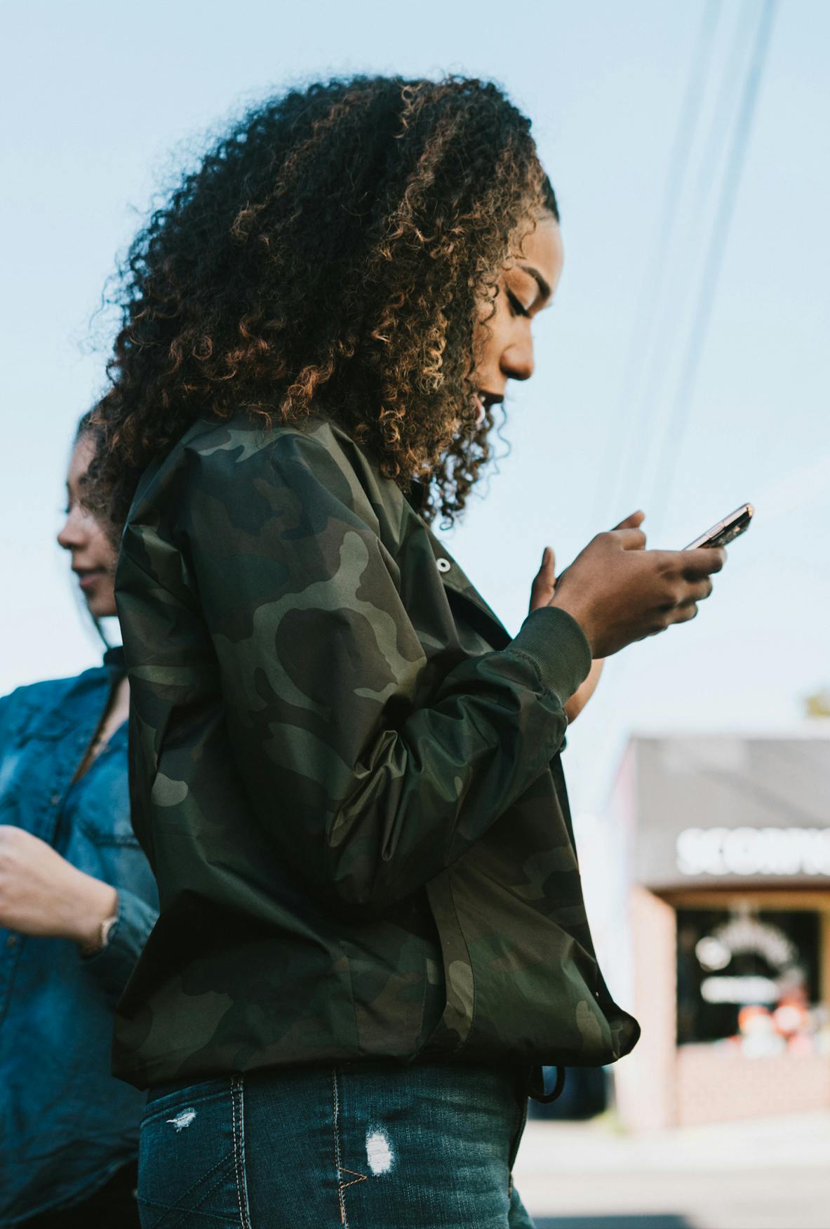 woman in camo jacket looking at smartphone exterior