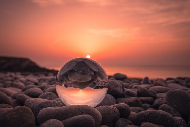 crystal ball on rock beach at sunset