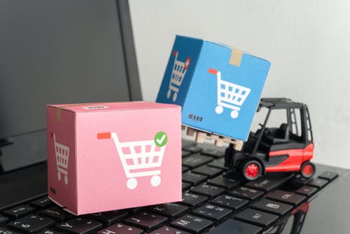 miniature forklift truck lifting boxes on laptop. via shutterstock