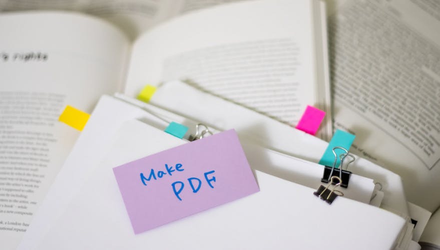 papers with 'make pdf' sticky note on top