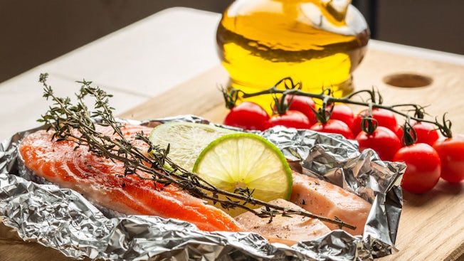 baked salmon in foil with herbs tomatoes and olive oil on the side