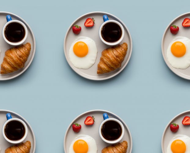 一盘又一盘的咖啡、煎蛋、草莓和牛角面包呈网格状排列
