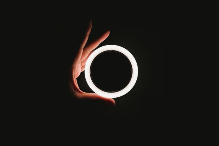 手抓发光的白色戒指在黑色的背景
