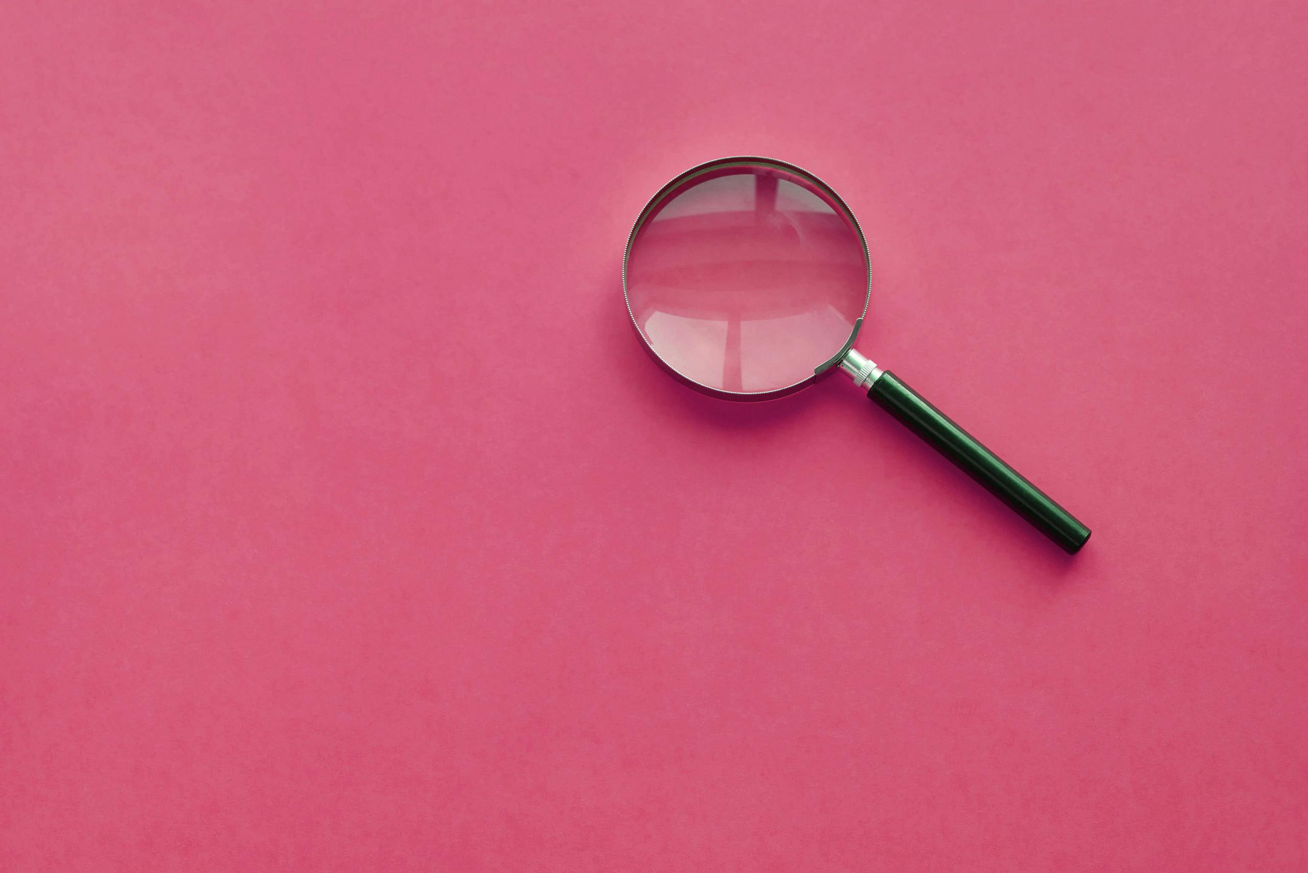 magnifying glass on deep pink background