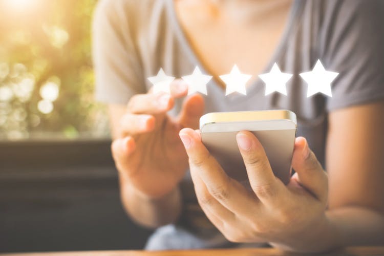 woman holding phone with 5 stars graphic