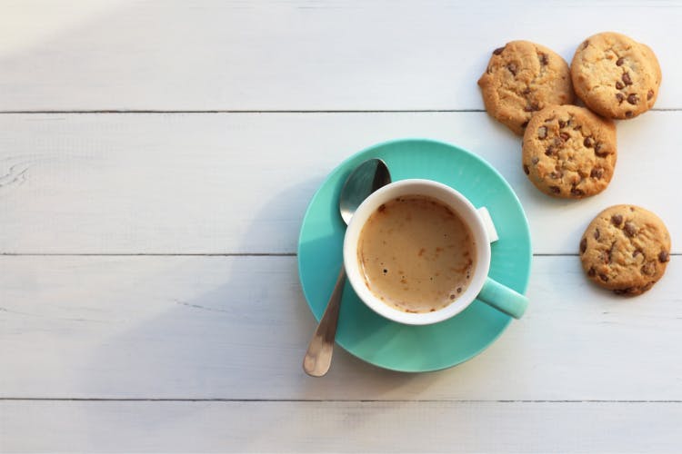 coffee in a turquoise cup on a saucer and cookies on a white background