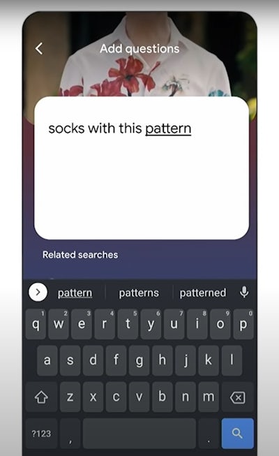 A smartphone screen with a text box overlaid on an image of a person wearing a colourfully patterned shirt. The text being input reads: socks with this pattern