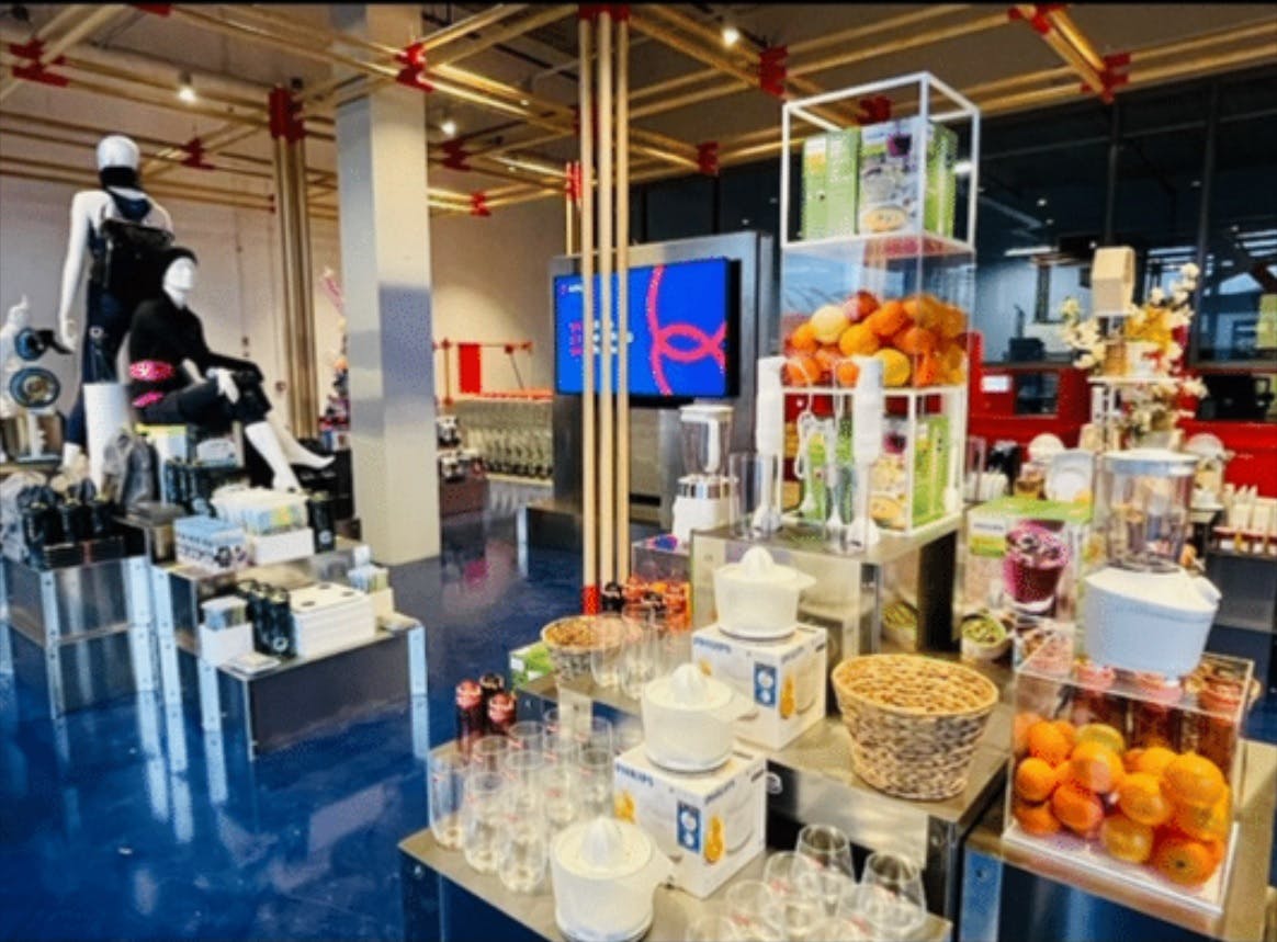 Photograph of store displays inside ochama, which feature fresh fruit, cooking appliances and crockery arranged in an aesthetically appealing way. In the background are some mannequins modelling clothing.