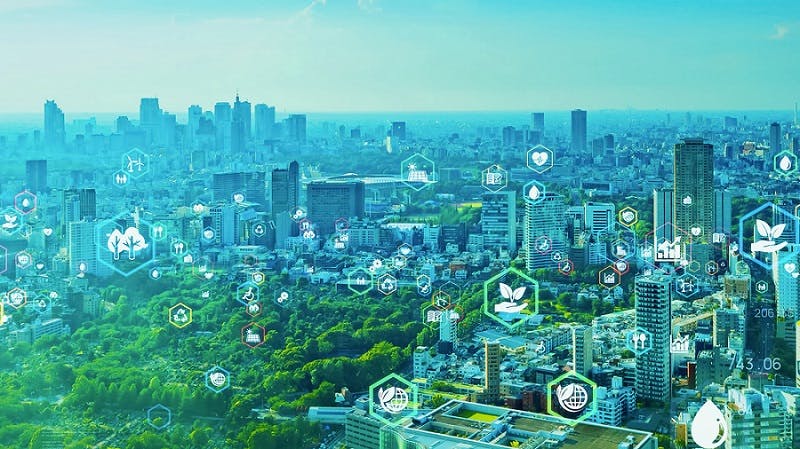 Stock imagery of a city overlaid with icons representing sustinability, e.g. trees, a hand cupping a seedling, a recycling symbol, a globe with a leaf curled around it, etc.