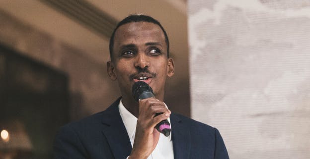 Yahye Siyad holding a microphone while speaking at an event