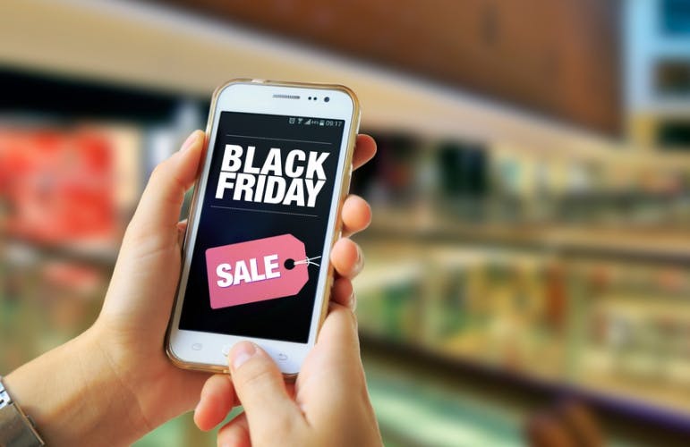 Hands holding a mobile phone displaying Black Friday sale text.