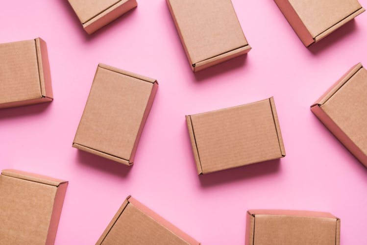 several brown cardboard boxes scattered on a pink background