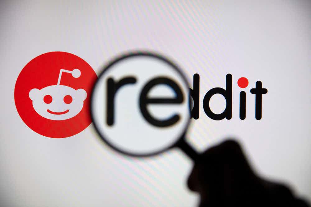 A magnifying glass held over the Reddit logo, causing the RE to appear larger.