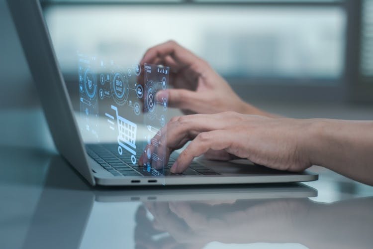 hands using laptop with shopping trolley hologram