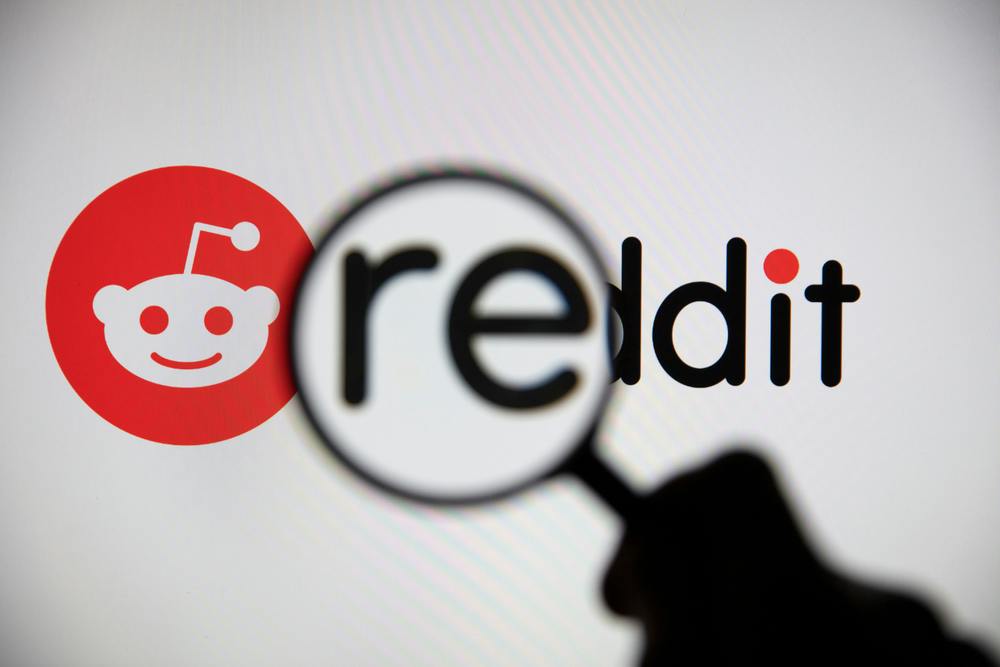 A magnifying glass held over the Reddit logo, causing the RE to appear larger.