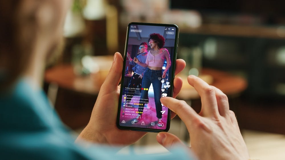 Stock image of a person holding a smartphone and engaging with a video stream.